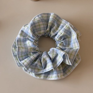 Detailed close-up of blue and green plaid scrunchie with cotton fabric and fine stitching
