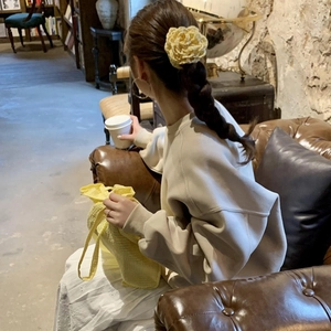 Detailopname van een gele bloem haarklem gestyled op een gevlochten kapsel voor dames