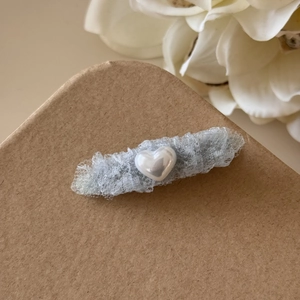 Détail d'une pince à cheveux en dentelle bleu clair avec cœur perlé sur papier kraft