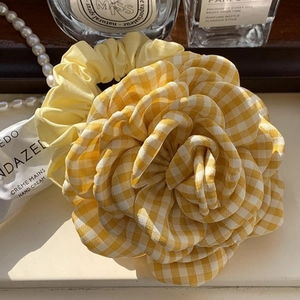 Gedetailleerde close-up van een geel geblokte roos haarklem met elegante accessoires