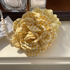 Detailopname van een gele geruite rozen haarklem met een elegante textuur van ruitjesstof