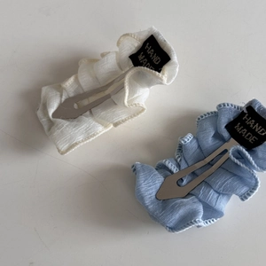 Vue détaillée des barrettes en tissu crème et bleu clair avec étiquettes faites à la main
