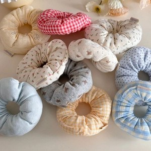 Detailed flat lay of nine assorted floral and plaid fabric scrunchies in pastel colors