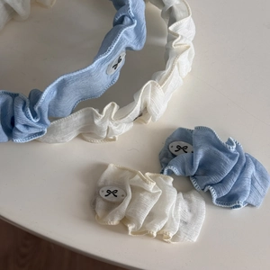 Détail de chouchous bleu clair et beige avec bords en dentelle et breloques en résine