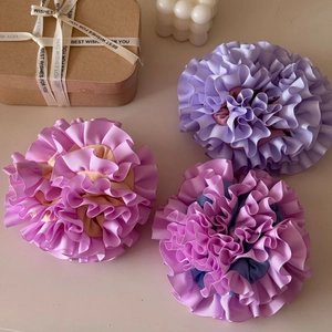 Three oversized handmade carnation ruffle scrunchies in pastel purple and pink satin fabric