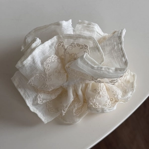 Détail d'un chouchou en dentelle blanche avec broderie fine au style rétro français
