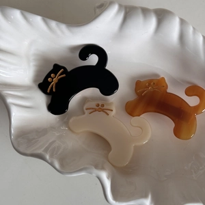 Detailed close-up of cat-shaped acetate hair clips in black, cream, and amber tortoise shell