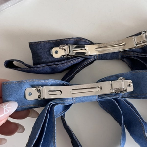 Detailansicht der Metall-Haarklammer und der gelben Nähte auf blauen Denim-Schleifen