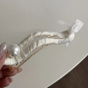 Détail de la pince à cheveux avec nœud en dentelle crème et grande perle blanche élégante