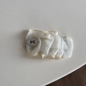 Vue détaillée de la dentelle blanche translucide avec un charme de nœud noir en résine