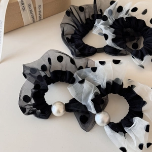 Detail of mesh polka dot scrunchie with large pearl accent and elegant pleated texture