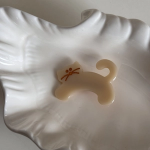 Detail of cute cream acetate cat hair clip with gold glitter whiskers on white tray