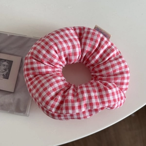 Detail of red and white gingham fabric scrunchie with soft padding and side label