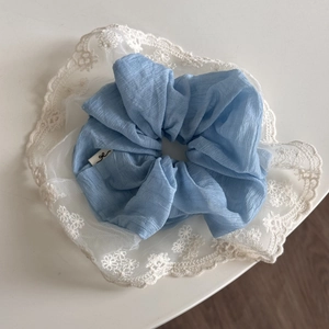 Détail du chouchou bleu clair avec bordure en dentelle blanche élégante et texture douce