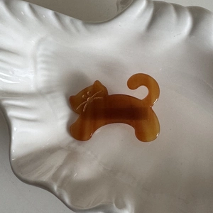 Macro detail of amber acetate cat hair clip with marble texture on ceramic plate