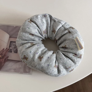 Close-up of grey knit floral scrunchie with cute bear patterns and textured fabric