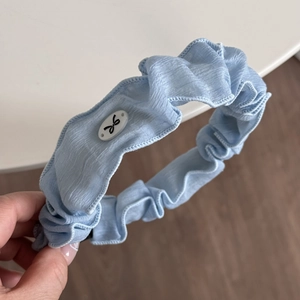 Détail de la texture du chouchou plissé bleu clair avec boucle à nœud blanc