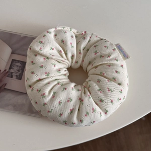 Detailed macro view of an oversized floral scrunchie with soft pink blossoms and embroidery