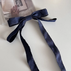 Detail der dunkelblauen Denim-Schleife-Haarklammer mit Kontrastnähten und Bändern