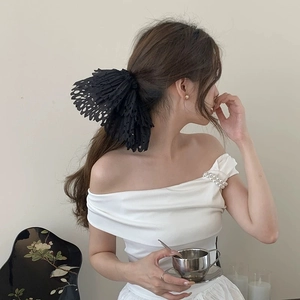 Close-up of black hollow lace bow hair tie worn on a ponytail for an elegant look