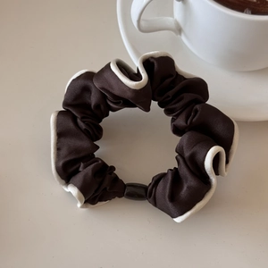 Detail of dark coffee satin hair scrunchie with cream contrast piping and secure buckle