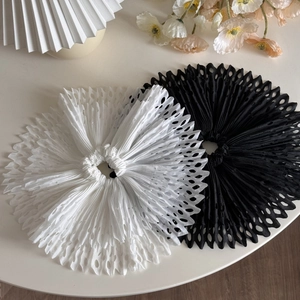 Detailed macro view of black and white pleated scrunchies with intricate hollow-out edges