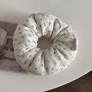 Close-up of cream knit floral scrunchie with pointelle texture and blue flower patterns