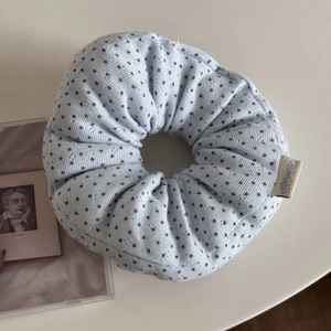 Detail of light blue polka dot hair scrunchie with woven label on a white background