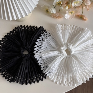 Detailed close-up of black and white hollow out pleated hair scrunchies with laser-cut patterns