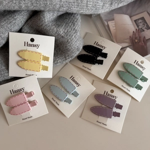 Close-up of matte resin hair clips in six pastel colors with stitched texture detail