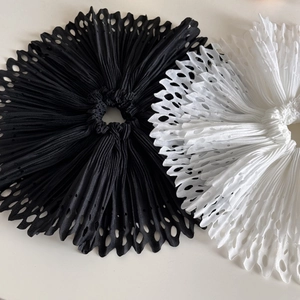 Detailed macro view of black and white laser-cut pleated fabric hair accessories