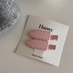 Detail of pink hair clips with stitching texture on white handmade display card