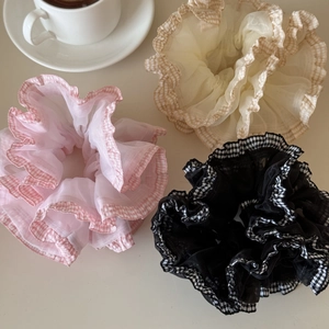 Close-up of three plaid mesh hair scrunchies in pink, beige and black colors