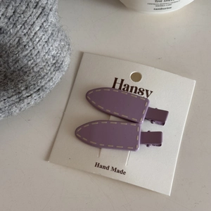 Detail of purple resin hair clips with cream stitching on a handmade display card