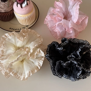 Close-up of oversized plaid mesh hair scrunchies in pink and beige with ruffled edges