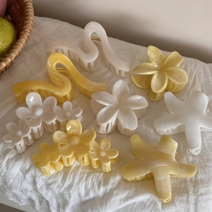 Dettaglio delle mollette per capelli in acetato a forma di fiore su tessuto bianco