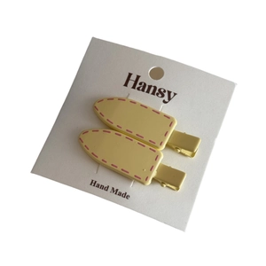 Set of two pale yellow Korean hair clips with pink stitching on white brand card