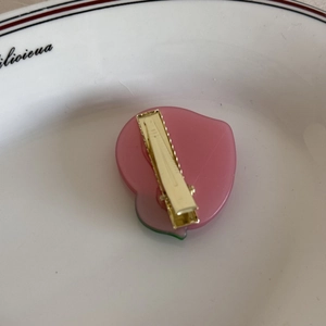Vista dettagliata della molletta a pesca rosa che mostra la clip a becco d'anatra dorata