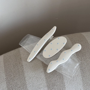 Détails de trois barrettes à cheveux en acrylique crème avec motifs à pois bleus