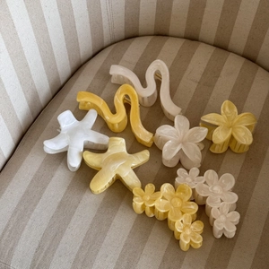 Pinza per capelli a forma di plumeria crema e gialla con trama marmorizzata su tessuto