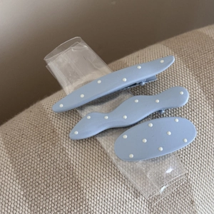 Gros plan de trois pinces à cheveux bleues à pois, formes ondulées et ovales