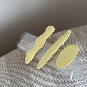 Détail d'un lot de barrettes à pois jaunes comprenant des formes vagues et ovales