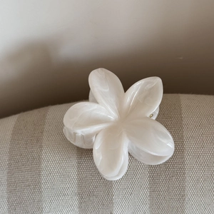 Dettaglio della pinza per capelli a fiore di plumeria crema con trama in marmo acetato
