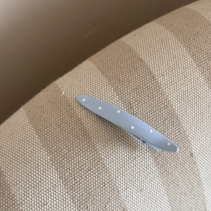 Détail d'une pince à cheveux bleu clair à pois blancs sur un tissu texturé