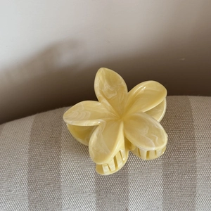 Dettaglio di una pinza per capelli a fiore giallo con trama marmorizzata bianca su tessuto