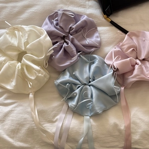 Vue détaillée de chouchous en satin avec perles blanches et longs nœuds en ruban