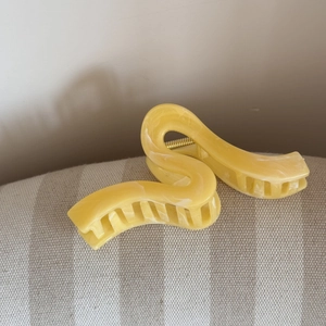Dettaglio della molletta per capelli gialla marmorizzata a forma di S con molla oro