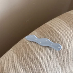 Gros plan d'une pince à cheveux bleue ondulée à pois blancs sur une surface tissée