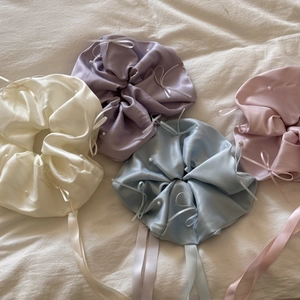 Détail de chouchous en satin assortis avec nœuds en ruban élégants et perles