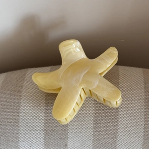 Dettaglio della pinza per capelli a stella marina con trama marmorea giallo crema